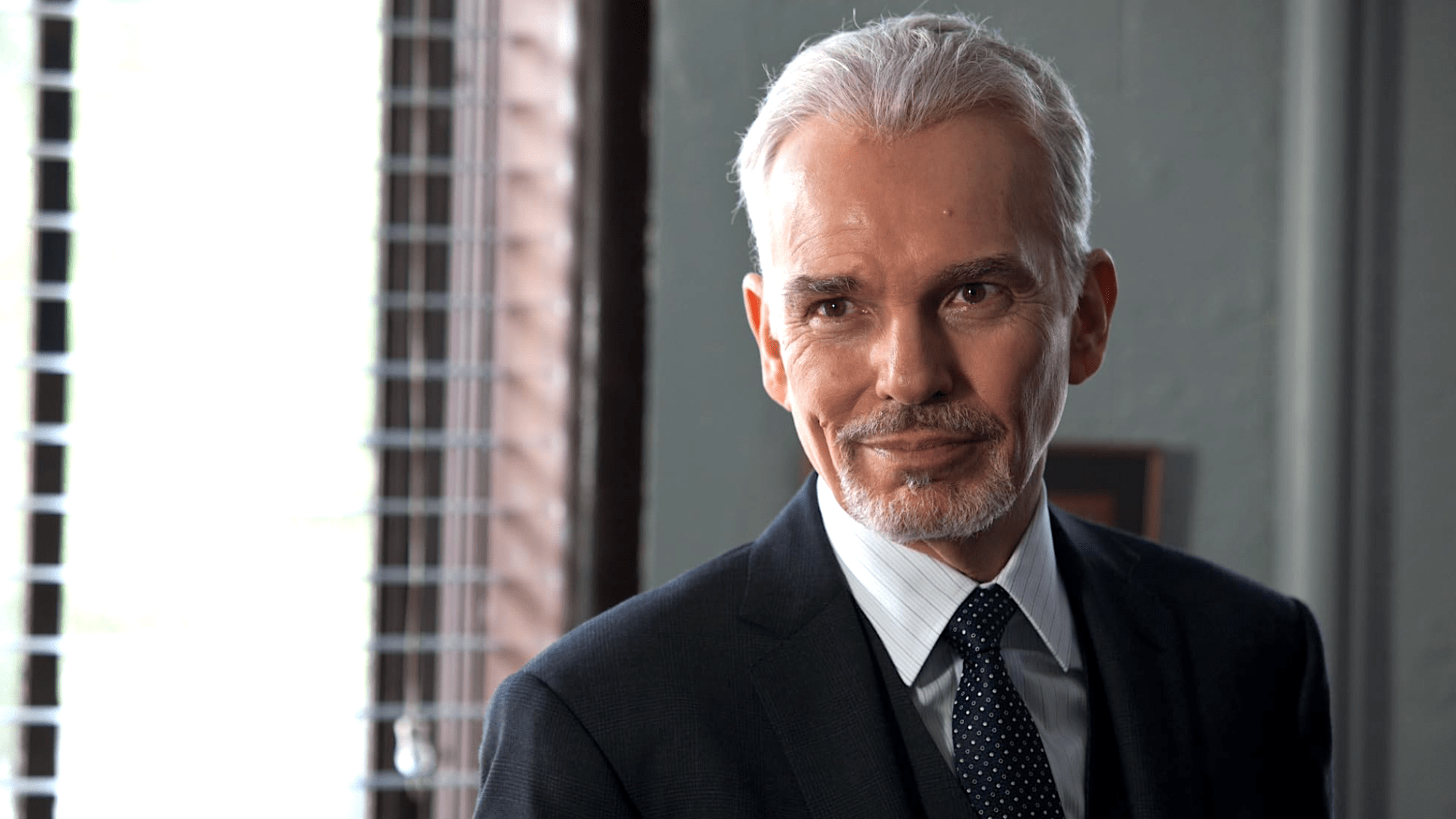 Billy Bob Thornton wearing a suit and smiling